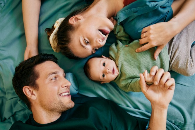 Junge Eltern liegen mit ihrem Baby auf einer Decke